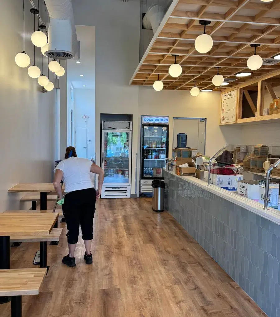 CleanieUp team member wiping down tables in a cafe dining area, a real job by our Winter Garden, FL crew