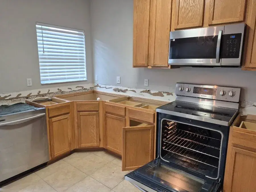 Empty kitchen with open cabinets and a stainless range during a CleanieUp move-out cleaning in Winter Garden, FL