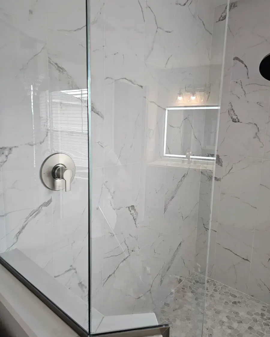 Marble-look walk-in shower with a clear glass door after a weekly house cleaning in Dr. Phillips, FL