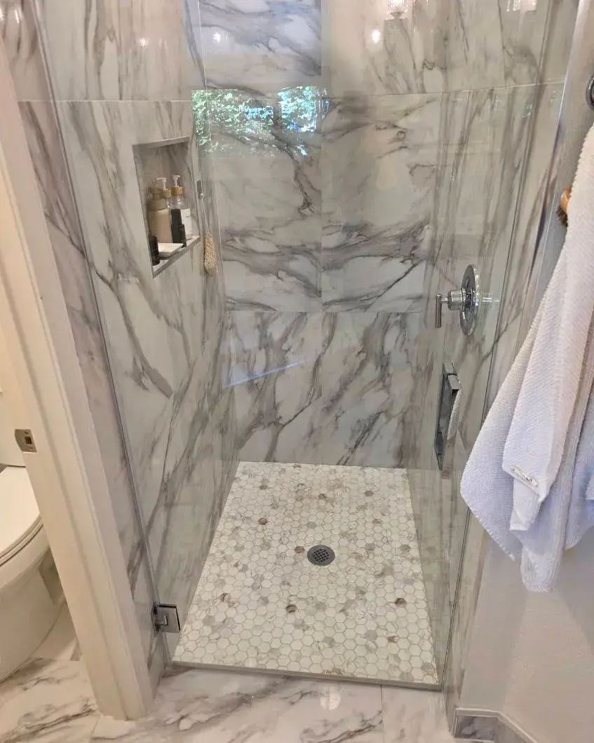 Marble-look shower with a pebble floor after a biweekly house cleaning in Minneola, FL