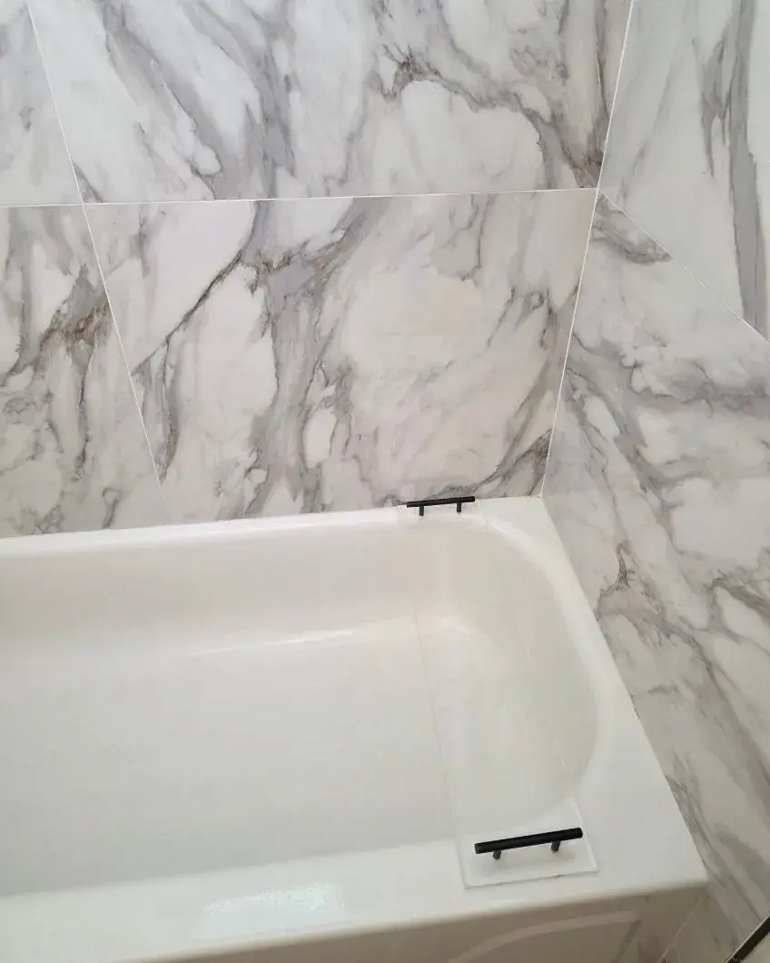 Bathtub with marble-look walls wiped clean after a monthly house cleaning in Minneola, FL