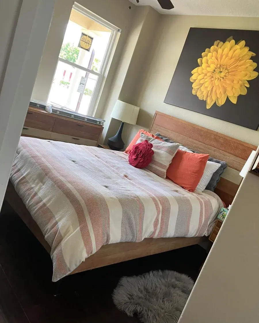 Freshly made bed with a striped comforter and bright pillows after a biweekly house cleaning in Montverde, FL