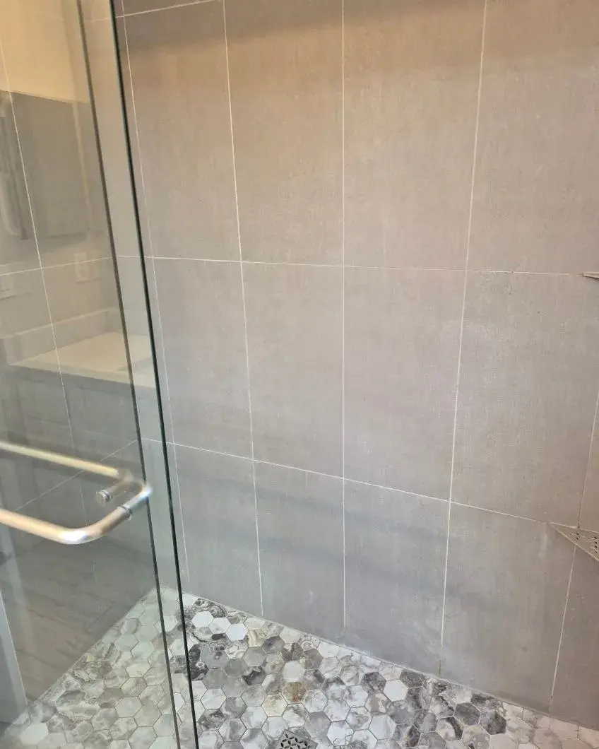 Glass shower enclosure with beige tile walls after a weekly house cleaning in Montverde, FL