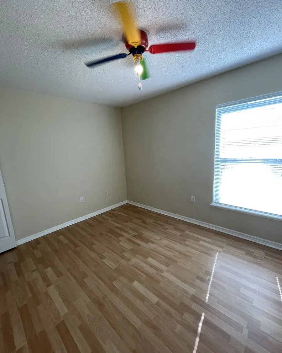 Empty bedroom with laminate floors and a bright window after a move-in cleaning in Oakland, FL