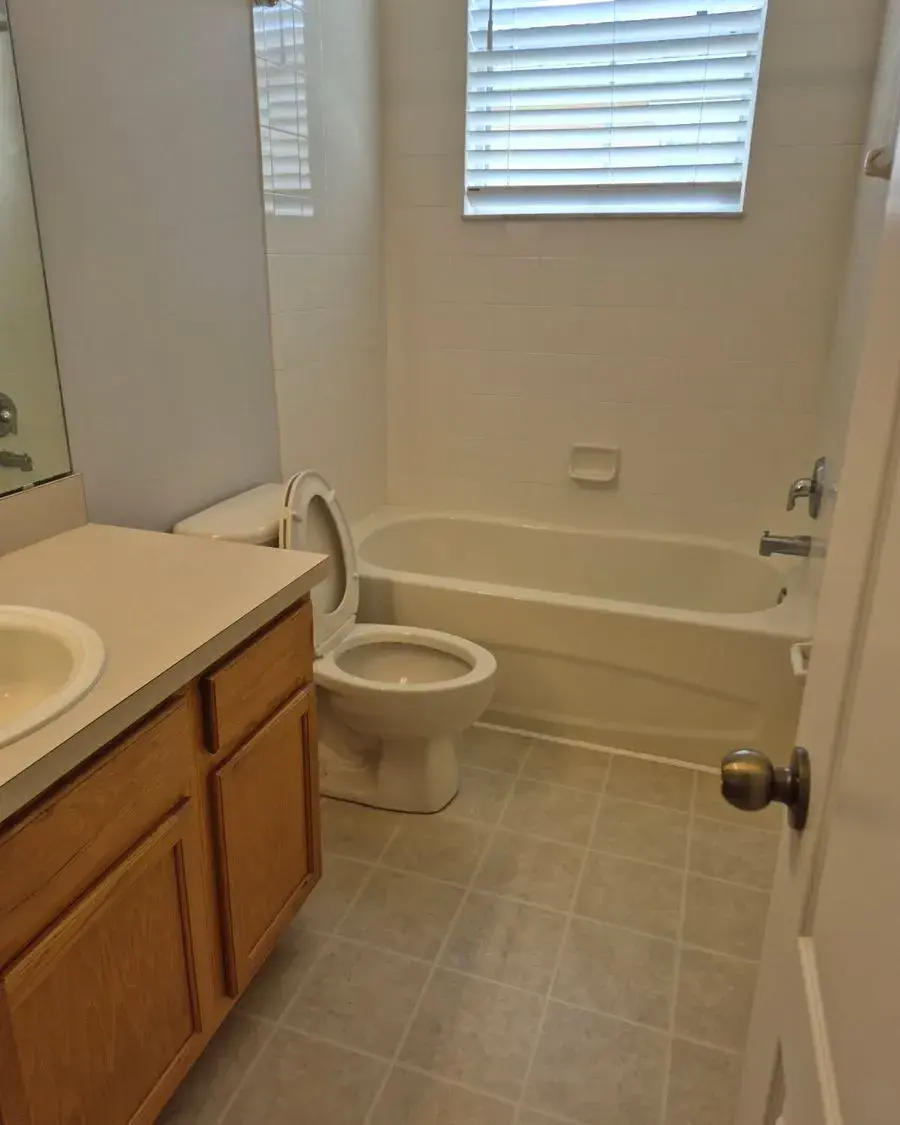 Bathroom with a clean tub, toilet, and vanity in an empty home after a move-out cleaning in Ocoee, FL