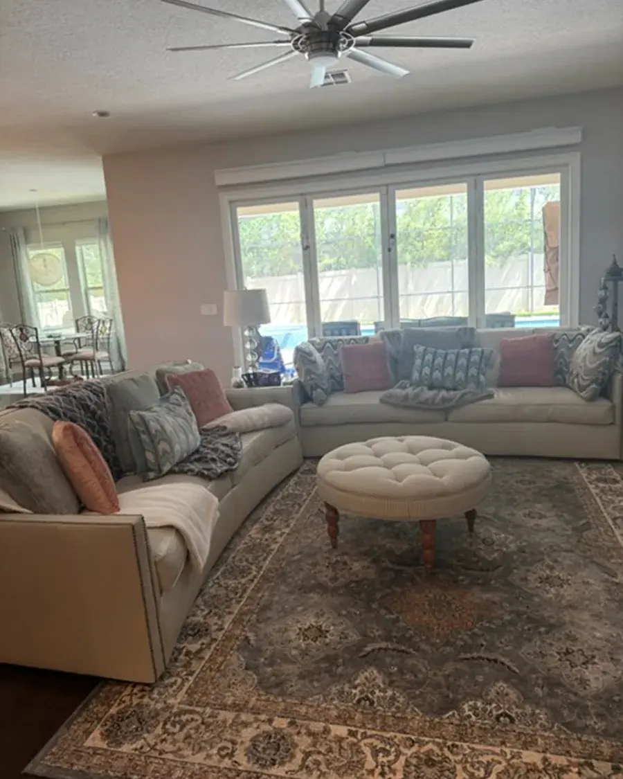 Living room with a curved sectional and a wall of bright windows after a monthly house cleaning in Windermere, FL