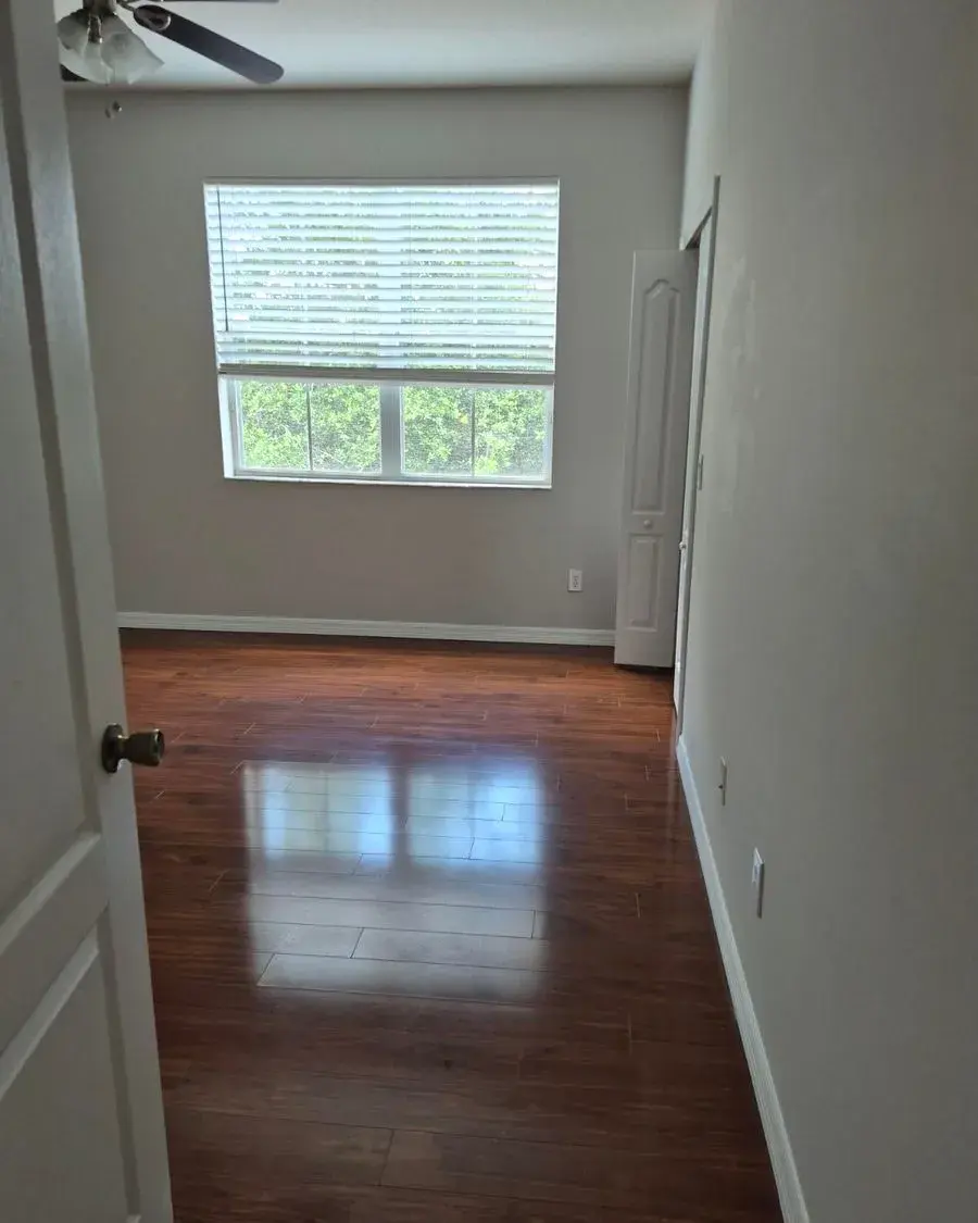Empty bedroom with gleaming hardwood floors and a sunny window after a move-out cleaning in Windermere, FL