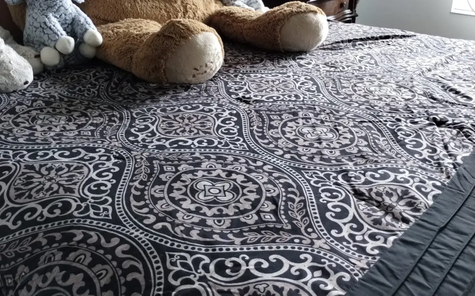 Made bed with a patterned comforter and a row of plush toys after a biweekly cleaning in Winter Garden, FL