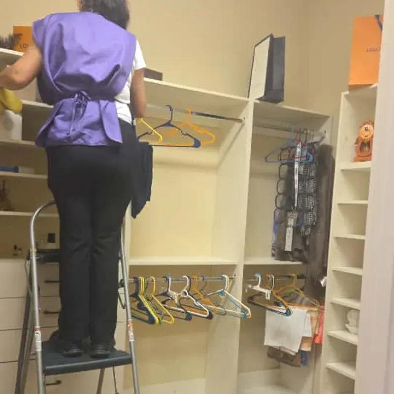 CleanieUp cleaner on a step stool dusting closet shelves during a home cleaning in Winter Garden, FL CleanieUp cleaner on a step stool dusting closet shelves during a home cleaning in Winter Garden, FL
