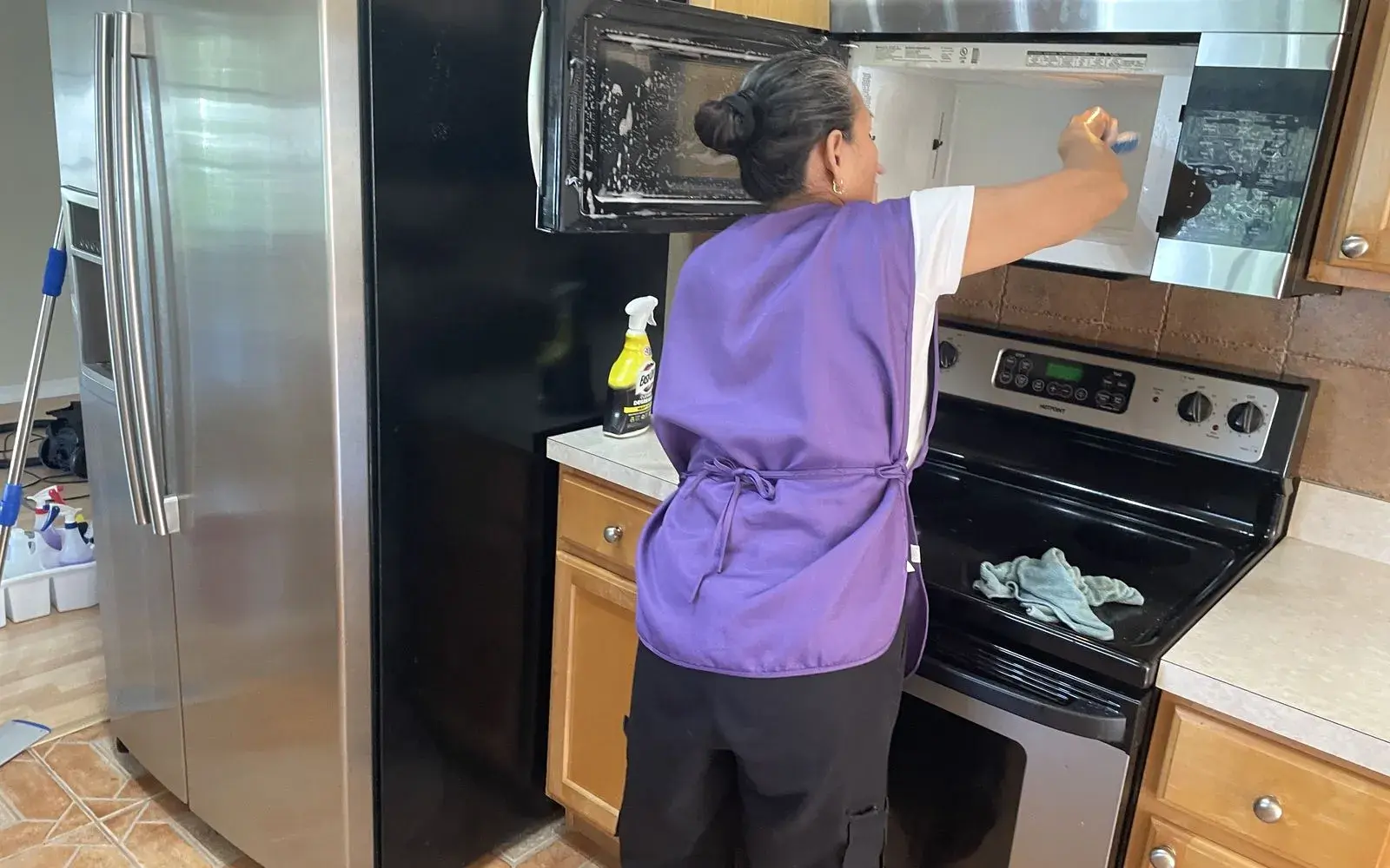 CleanieUp cleaner in a purple vest wiping a microwave during a deep cleaning in Winter Garden, FL CleanieUp cleaner in a purple vest wiping a microwave during a deep cleaning in Winter Garden, FL